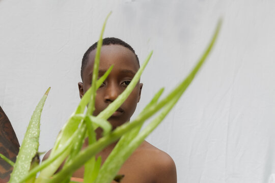 Child standing behind an aloe vera plant