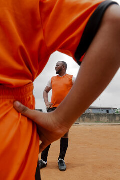 Father posing on soccer field in front of son with hands on hips