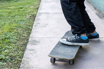 Close up of a young boy with tennis shoes on a skateboarding outside the house. Adolescence time concept. Copy space.
