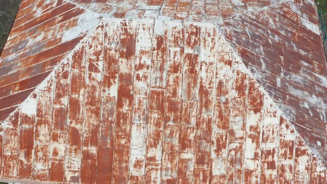 Rusty old tin roof on a house. Corrosion and oxidation of metal panels used for roofing. Aerial drone view.