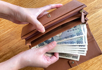 Woman hand pulling out Japanese money from a wallet