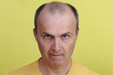 Portrait of a positive handsome man in a yellow T-shirt after 40 years.