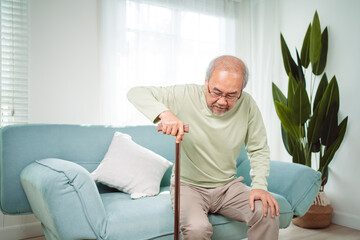 Asian Senior elderly old man disabled patient walking slowly his use walker or cane in living room at home. Feeling painful and suffering from knee pain. Healthcare medical and insurance concept.