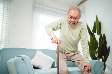 Asian Senior elderly old man disabled patient walking slowly his use walker or cane in living room...