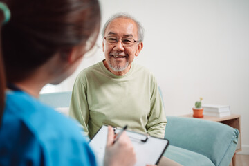 Asian caregiver talking senior male patient checkup in living room at home. Older elderly man consults after physical therapy. Nurse assistance rescue concept.