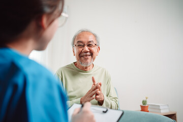 Asian caregiver talking senior male patient checkup in living room at home. Older elderly man consults after physical therapy. Nurse assistance rescue concept.