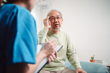 Asian caregiver talking senior male patient checkup in living room at home. Older elderly man consults after physical therapy. Nurse assistance rescue concept.