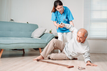 Asian caregiver helping senior male from falling on the ground. Older elderly man patient having accident heart attack when physical therapy. Nurse assistance rescue concept.