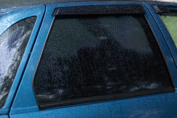 Tinted rear window of a car with raindrops