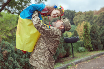 Ukrainian soldier is holding his daughter in his arms.