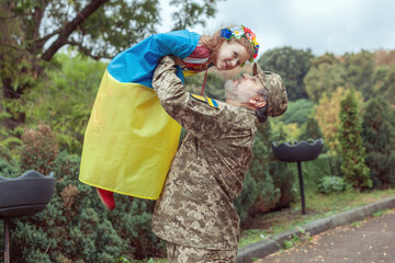 Ukrainian soldier is holding his daughter in his arms.