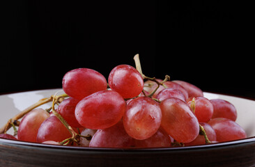 Bunch of ripe red grapes in a plate side view. Red grape Taifi