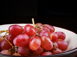 Bunch of ripe red grapes in a plate side view. Red grape Taifi