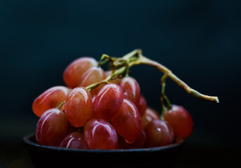 Bunch of ripe red grapes in a clay plate. Shallow depth of field.
