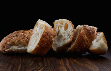 Fresh baguette cut into pieces on a wooden table. Art bread. Baguette with herbs.