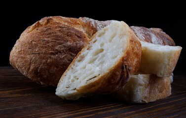 Fresh baguette cut into pieces on a wooden table. Art bread. Baguette with herbs and spices.