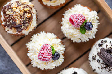 Tasty sweet muffins with mascarpone creme and chocolate, raspberry and blueberry. Fresh home baked sweets with fruit. Placed in wooden box.