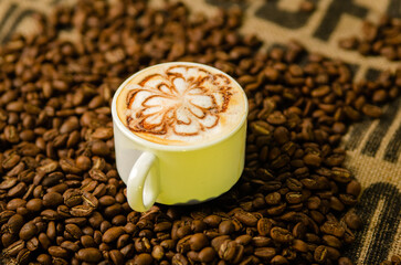 cup of cappuccino on a table with coffee beans