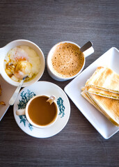 Asian traditional breakfast combination of half boiled eggs, toast bread with butter and kaya and coffee.
