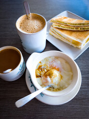Asian traditional breakfast combination of half boiled eggs, toast bread with butter and kaya and coffee.