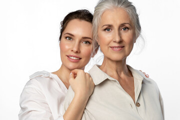 Daughter and her elderly mother, two beautiful women of different generations on a white background...