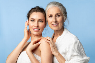 A young woman and her elderly mother take care of their skin and look great. Two generations of beautiful women on white background.
