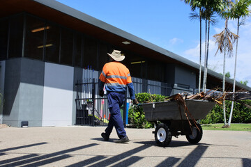 Public municipal worker pulling a wheelbarrow