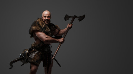 Portrait of aggressive scandinavian warrior with fur holding huge axe.
