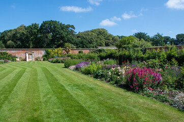 English walled garden with flowers and lawn - 538302789