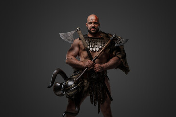 Naklejka premium Shot of bloodthirstly viking from past dressed in armor and fur against grey background.