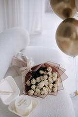 Decorated room at home for surprise party. Bouquet of flowers and banto cake on sofa. Few colorful balloons.Happy birthday for Eighteen-year-old girl