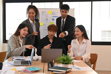 Group of experienced business people looking at laptop screen, celebrating project success, excited by good news or message