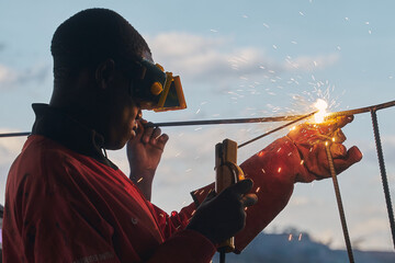 Sparks of hope. Young black man is welding.