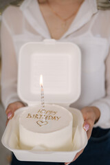 Girl hold bento cake decorated by golden inscription Happy Birthday. Cakes for one person. One candle in the middle of the cake