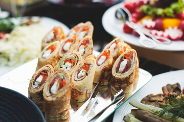 Catering table, beautifully decorated banquet with variety of with different food snacks appetizers on corporate birthday party event or wedding celebration, canape, salad, delicatessen setting
