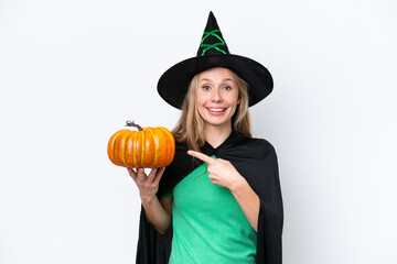 Young blonde woman dressed as a witch holding a pumpkin isolated on white background pointing to the side to present a product