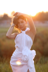 Fototapeta na wymiar Beautiful girl in a white light dress posing outdoors in the sun