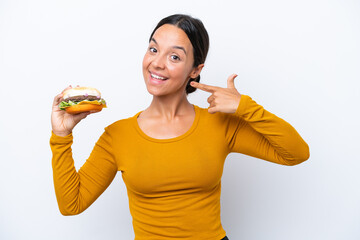 Young hispanic woman holding a burger isolated on white background giving a thumbs up gesture