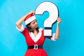 Young hispanic woman dressed as mama noel isolated on blue background holding a question mark icon