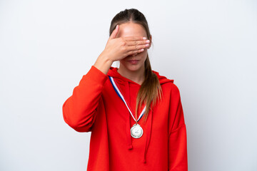 Young caucasian woman with medals isolated on white background covering eyes by hands. Do not want...