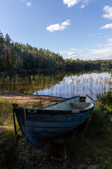 Old blue fiberglass boat on sandy beach in Repovesi National Park, Finland