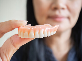 Happy asian woman  be smile and holding dentures in hand.