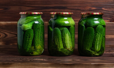 Preservations, conservation. Salted, pickled cucumbers in a jar on an old wooden table. Cucumbers, herbs, dill, garlic.