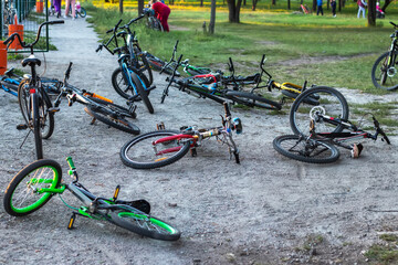 Many bicycles lie on the ground near the sports ground