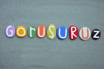 Gorusuruz, turkish word meaning, see you later, composed with multi colored stone letters over...