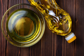 Sunflower oil in bottles with glass bowl on wooden background. Top view