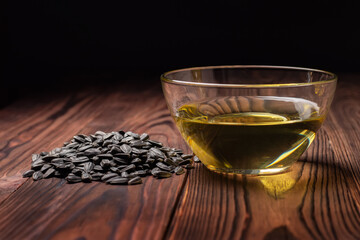Sunflower oil in glass bowl with seed pile on wooden desk