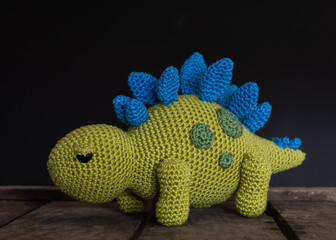 Green and blue stegosaurus on wooden box with black background, toy, handmade, crochet, hobby   © Katrien