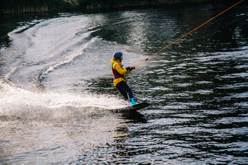 A guy in a yak suit at sunset jumps from a springboard on a wakeboard in an extreme park in Kiev. Ukraine.