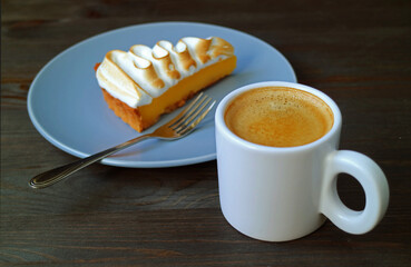 Closeup a Cup of Coffee with Blurry Lemon Meringue Tart in the Backdrop